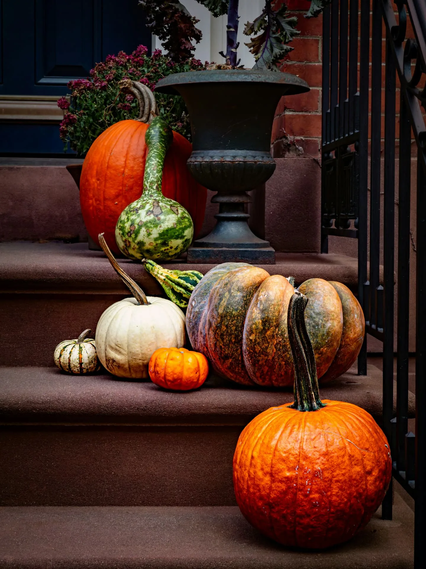Front steps styled with pumpkins, gourds and an iron urn